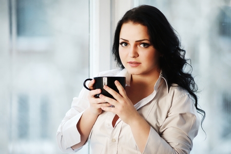 Portrait of young woman holding a cup of coffee.の写真素材