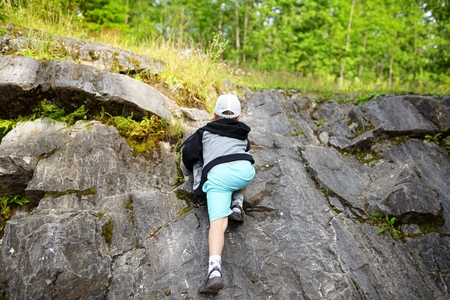 Young caucasian child boy climbing rocks in forestの写真素材