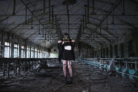 Beautiful, young girl post apocalypse girl stand in abandoned factory with gas maskの写真素材