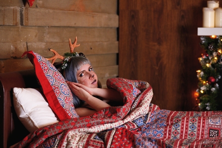 Beautiful girl in a Christmas deer costume lie in bedの写真素材
