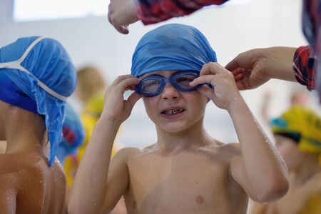 Little boy straightens his swimming goggles in poolの写真素材