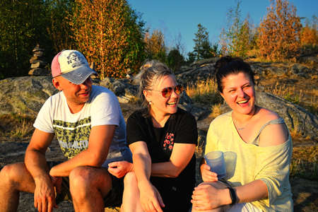 Three friends sitting on rocks and smilingの写真素材