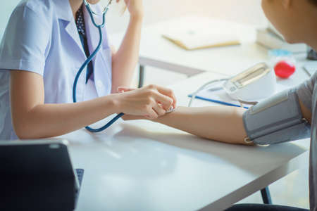 doctor woman checking blood pressure of male patient and heart rate with digital pressure gauge ,Cardiology in medicine and health care conceptの写真素材