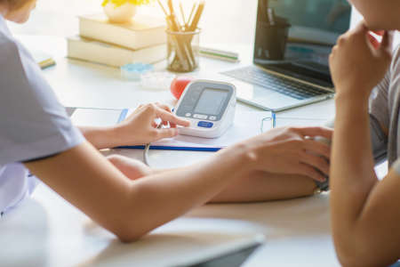 doctor woman checking blood pressure of male patient and heart rate with digital pressure gauge ,Cardiology in medicine and health care conceptの写真素材