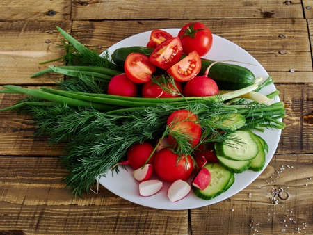 vegetables tomatoes cucumber green onion on the boardの写真素材