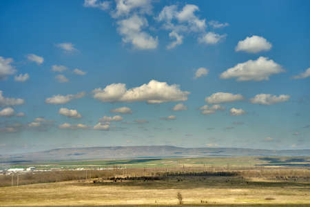 Spring distant hills, field, blue sky with clouds north caucasusの写真素材