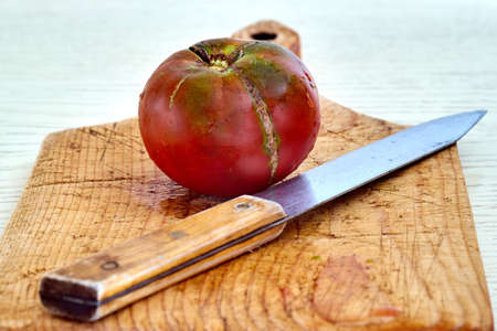 red ripe tomato on a cutting board with a knife