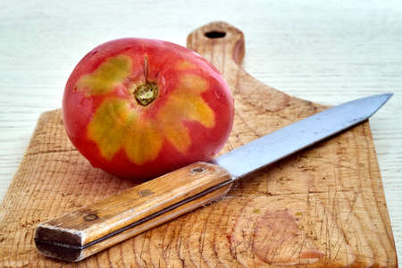 red ripe tomato on a cutting board with a knifeの写真素材