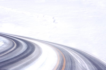 Tire tracks on the road by the snow fieldの写真素材