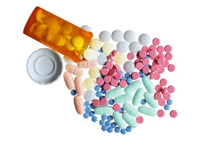 Orange bottle and colorful pills isolated on whiteの写真素材