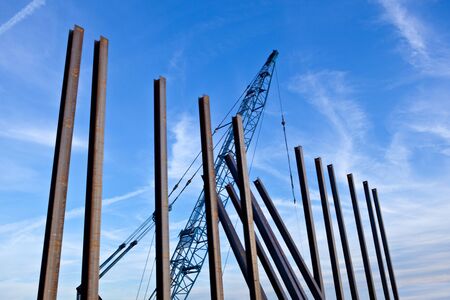Crane and vertical metal poles against the skyの写真素材