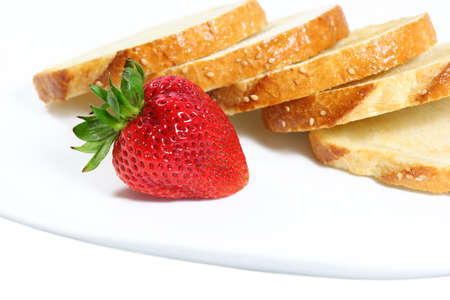 Single strawberry fruit and slices of breadの写真素材