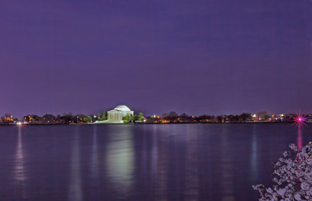 Thomas Jefferson Memorial illuminated at night with the tidal basin in the foreground during the peak cherry blossom festivalの写真素材