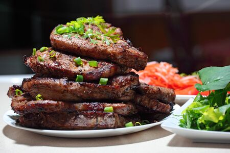 Delicious juicy grilled pork chop steak with fresh homegrown vegetable salad, tomatoes, sweet and...