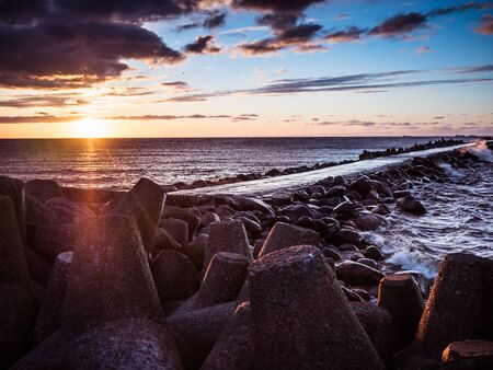 Sunset on the coast of the Riga Gulf at dawn with rocks in foregroundの写真素材