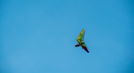 hang-glider flying along blue sky at sunny dayの写真素材