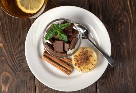 Plate with sweets: chocolate, sweets, honey, cinnamon and mint on a natural background. The concept of relaxation, eating.の写真素材