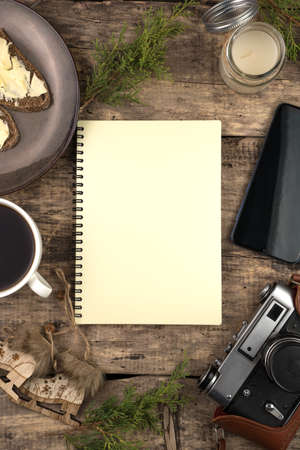 Notepad, Coniferous branches, coffee and sandwiches, phone and retro camera on the background of natural wood. Christmas composition. The concept of New year and Christmas.の写真素材