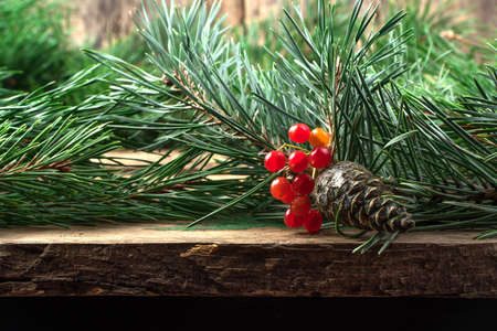 Pine cone and branches and a sprig of mountain ash on a natural wooden background. Holiday background. The concept of Christmas, New year.の写真素材