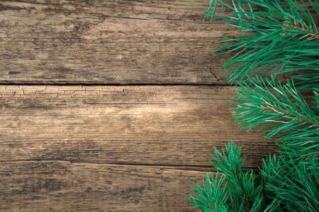 Festive Christmas background made of fresh pine branches on a natural wooden background. Holiday...