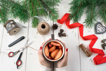 Break with a Cup of mulled wine while preparing for the Christmas holidays. Womens hands hold a mug...