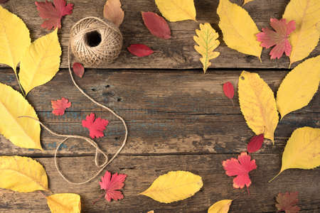 Autumn composition of leaves and threads in a ball on a natural wooden background. Autumn-winter background with space to copy. The concept of thanksgiving or Halloween.の写真素材