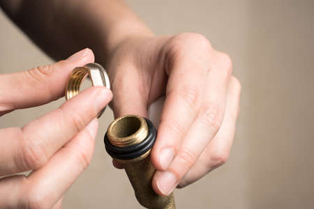 The plumbers hands Unscrew the nut from the valve tap. Side view. Concept of repair work.