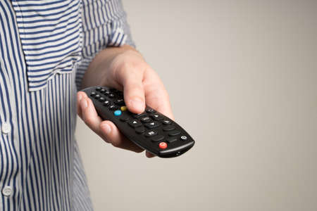 Remote control in the hands of a woman on a beige background. Concept of leisure at home.の写真素材