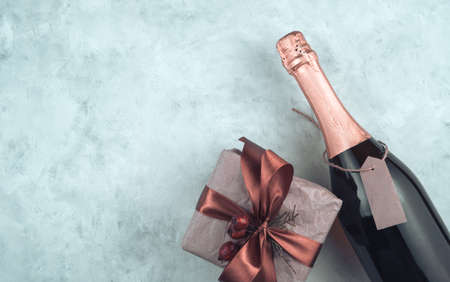 Stylized Christmas background with a bottle of alcohol and a gift box on a light background. The view from the top. The concept of New year and Christmas.の写真素材