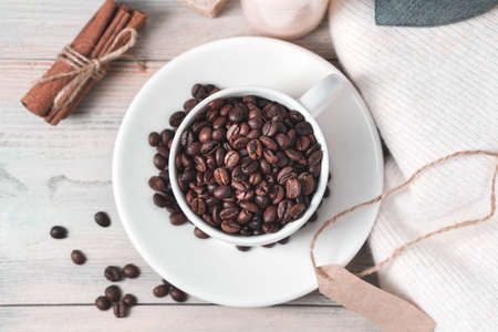 Aromatic coffee beans in a white ceramic Cup and saucer on an atmospheric light wooden background. The view from the top. Cafe concept.の写真素材
