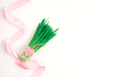 Satin pink ribbon bouquet with a heart on a light background. Top view with space to copy.