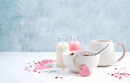 Breakfast on a romantic background. Cereal in a white Cup, coffee with milk and hearts on a blue and white background. Side view with space for copying. Concept of February 14, womens day.の写真素材