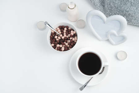 Chocolate and cereal balls, a Cup of coffee and a bottle of milk on the background of a frame with hearts and candles. The view from the top. Concept February 14.の写真素材