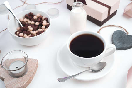 A Cup of coffee and a plate with wheat balls on a festive background with hearts and a gift on a...
