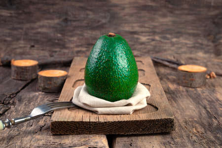 Avocado on a natural wooden background. Side view. The concept of proper nutrition.