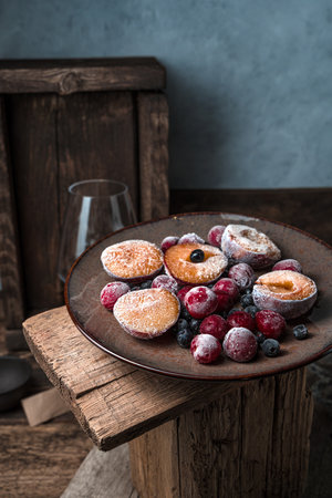 Still life with frozen berries and fruits in a brown plate on a vintageの写真素材