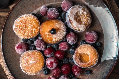 Frozen berries, plums and cherries in a brown plate on a woodenの写真素材