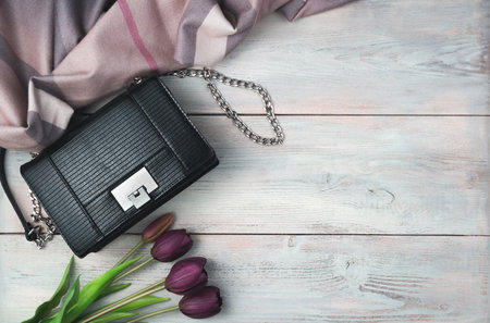 Festive background with Bag, scarf and tulips on light wooden background. Top view with space to copy. Concept of March 8.の写真素材