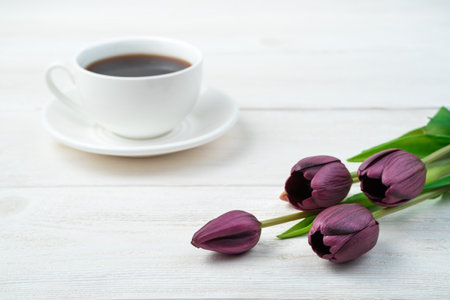 Purple tulips and a white coffee cup in the background on a light wooden background. Side view, with space to copy. Concept of March 8, spring.の写真素材
