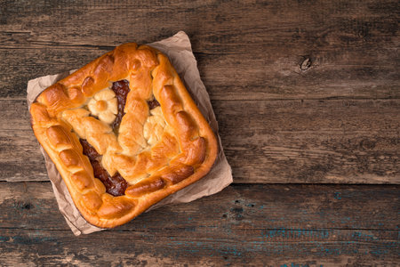 Homemade apple pie on kraft paper on a brown wooden background. Top view, with a space for copying. The concept of culinary backgrounds.の写真素材