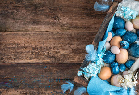 Easter background with marble blue and pastel quail and chicken eggs, decorated with blue feathers...