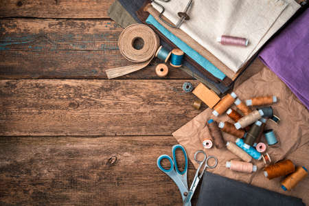 A set of fabrics, threads and other sewing accessories on a wooden background. Horizontal view.の写真素材