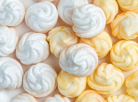 White and yellow meringues in a plate on a light background with a napkin. Side view with copy space.の写真素材