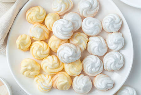 Yellow and white meringues on a light background close-up. Top view, horizontal. The concept of...