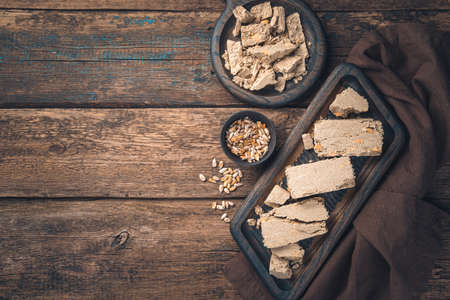 Sliced halva on boards and seeds on a brown background. Culinary background with space to copy.の写真素材
