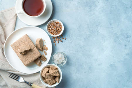 Halva with seeds and tea on a light blue background. Top view with copy space. Dessert concept.の写真素材