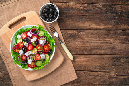 Greek salad and olives on a brown background. Top view with copy space. The concept of healthy eating.の写真素材