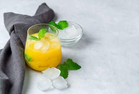 Orange drink with ice and mint on a gray background. Side view with copy space.の写真素材