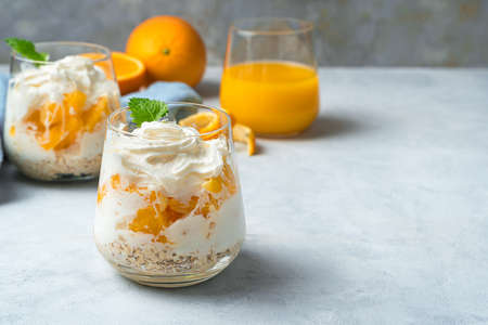 Orange dessert with cream and mint on a gray background. Whipped cream and fruit. Dessert concept.の写真素材