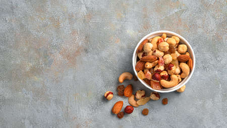 Mixed nuts and dried fruits on a gray background. Top view, copy space. Healthy snacks.
